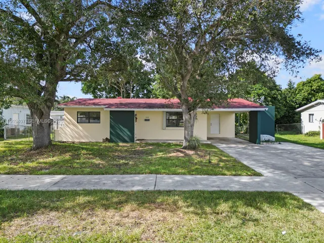 a view of a house with a yard and large tree