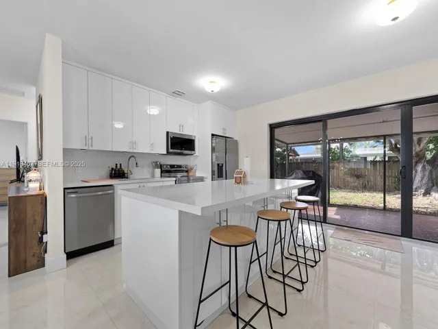 a kitchen with stainless steel appliances granite countertop a stove top oven a sink dishwasher a dining table and chairs with wooden floor