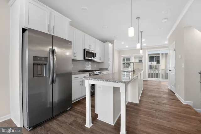 a kitchen with stainless steel appliances granite countertop a sink a oven a stove and a wooden floors
