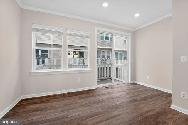 a view of an empty room with wooden floor and windows