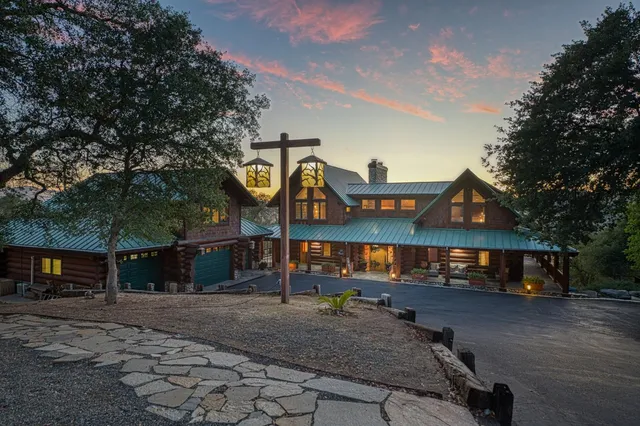 a view of a house with large tree and wooden fence