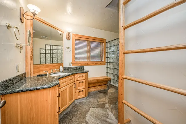 a bathroom with a granite countertop toilet a sink a mirror and shower