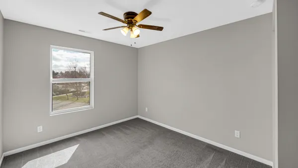 an empty room with a window and a fan