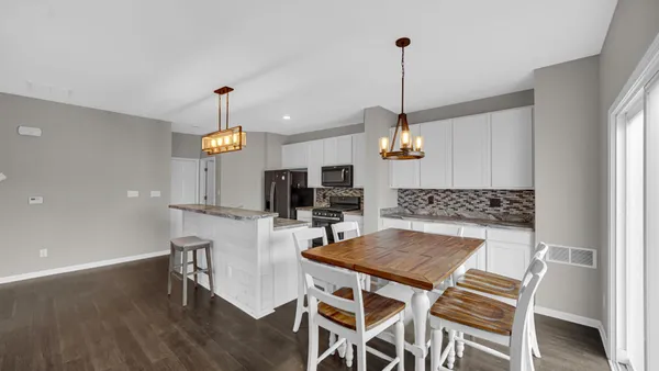 a kitchen with a dining table chairs and white cabinets