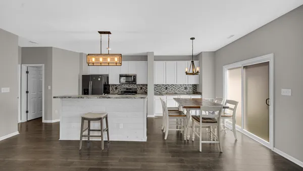 a kitchen with stainless steel appliances granite countertop a stove top oven a refrigerator a sink and a dining table with wooden floor