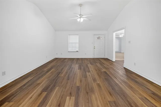 an empty room with wooden floor and a ceiling fan