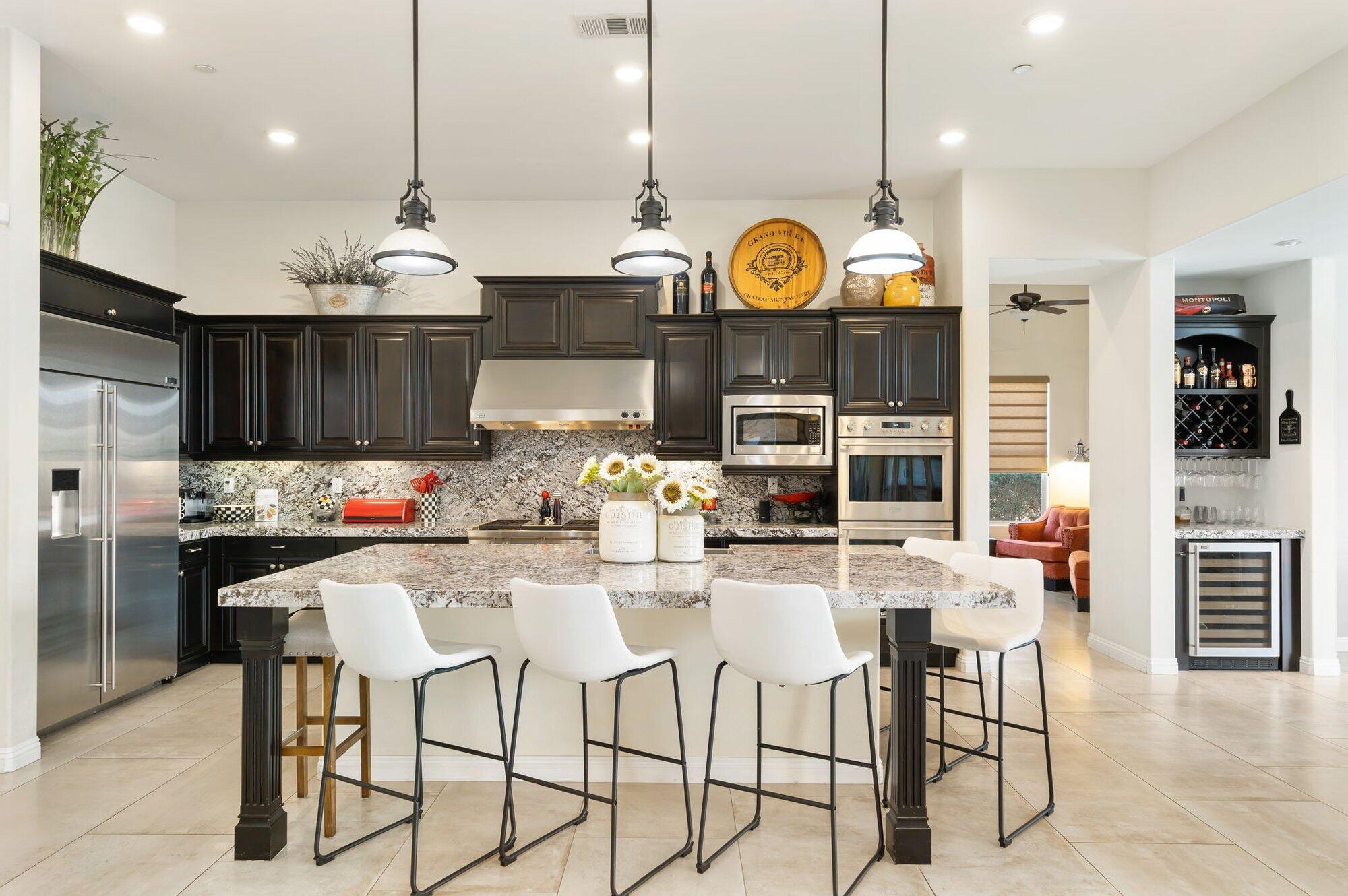 81675 Macbeth Street La Quinta, CA 92253 - Photo 22 of 76 a kitchen with stainless steel appliances kitchen island granite countertop a stove a refrigerator a oven a sink a dining table and chairs with wooden floor