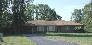 a front view of a house with a garden and trees