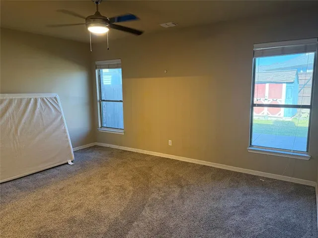 an empty room with windows and fan