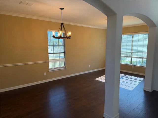 an empty room with wooden floor windows and entrance