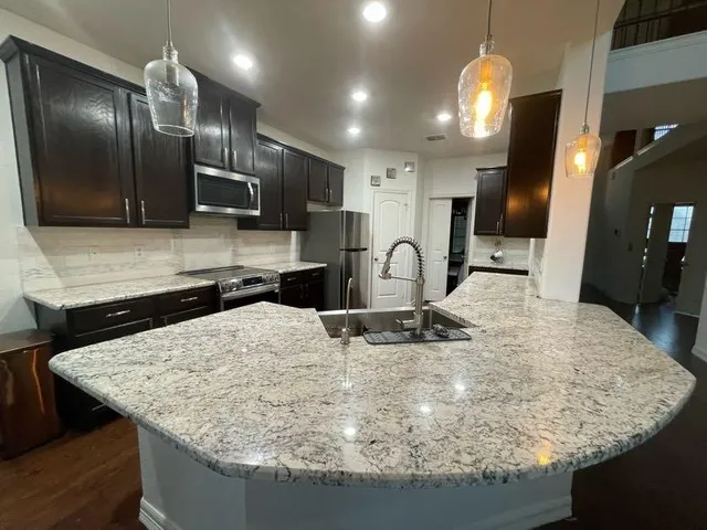 a kitchen with stainless steel appliances granite countertop a sink a stove and a refrigerator