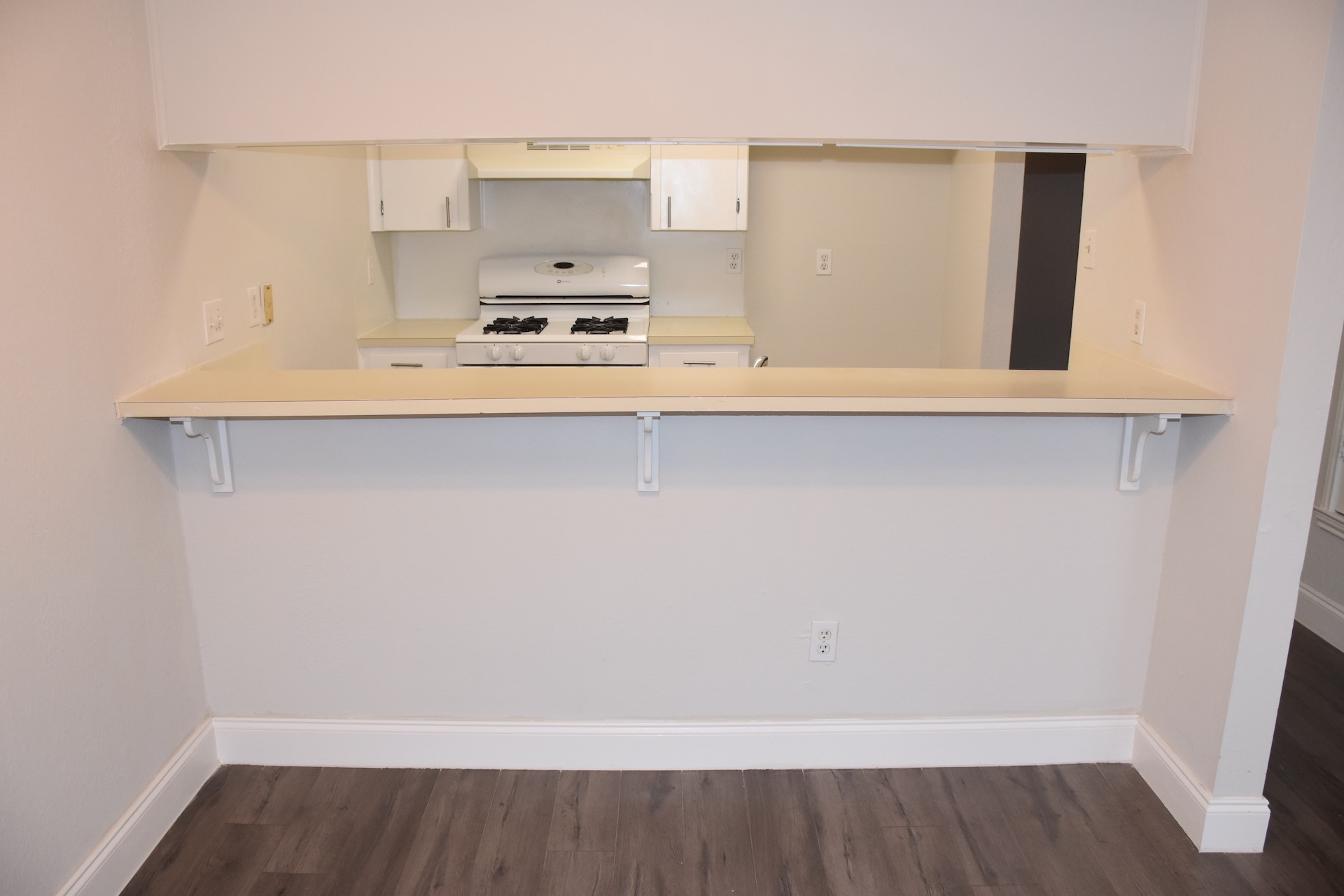 1810 Rawhide Loop Round Rock, TX 78681 - Photo 13 of 29 Kitchen pass-through with a breakfast bar, white cabinetry, a gas range, and wood-finish flooring