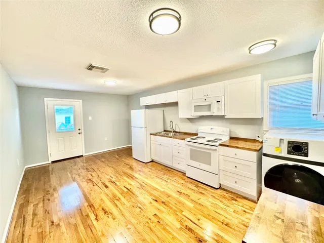 a kitchen with granite countertop a stove a sink and white cabinets