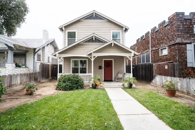 a front view of a house with a yard and potted plants