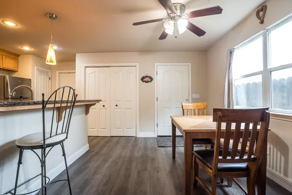 a kitchen with stainless steel appliances granite countertop a stove top oven a sink a dining table and chairs with wooden floor