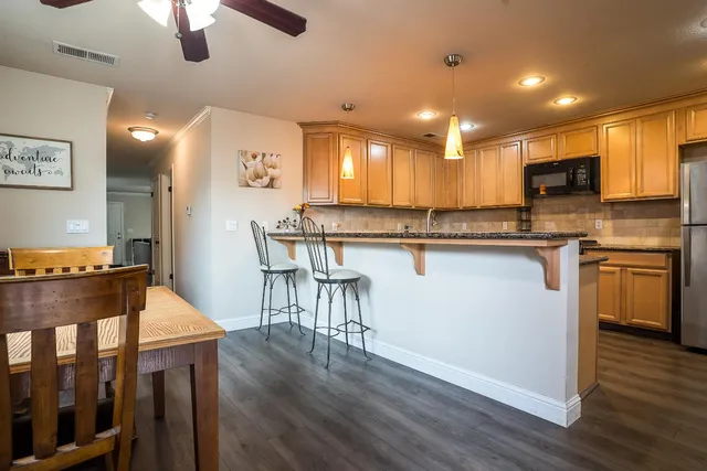 a kitchen with stainless steel appliances granite countertop a stove top oven a sink a dining table and chairs with wooden floor