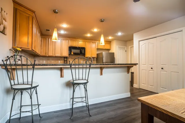 a kitchen with kitchen island granite countertop wooden floor and a refrigerator