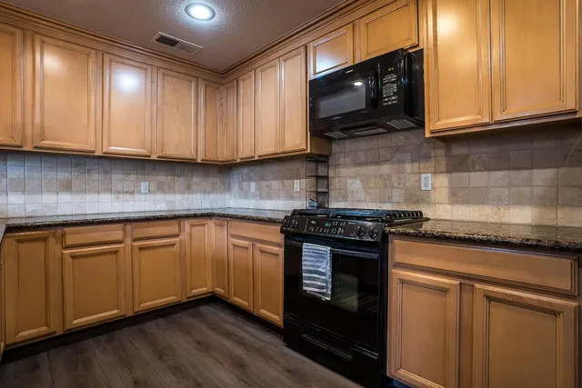 a kitchen with granite countertop wood cabinets and stainless steel appliances