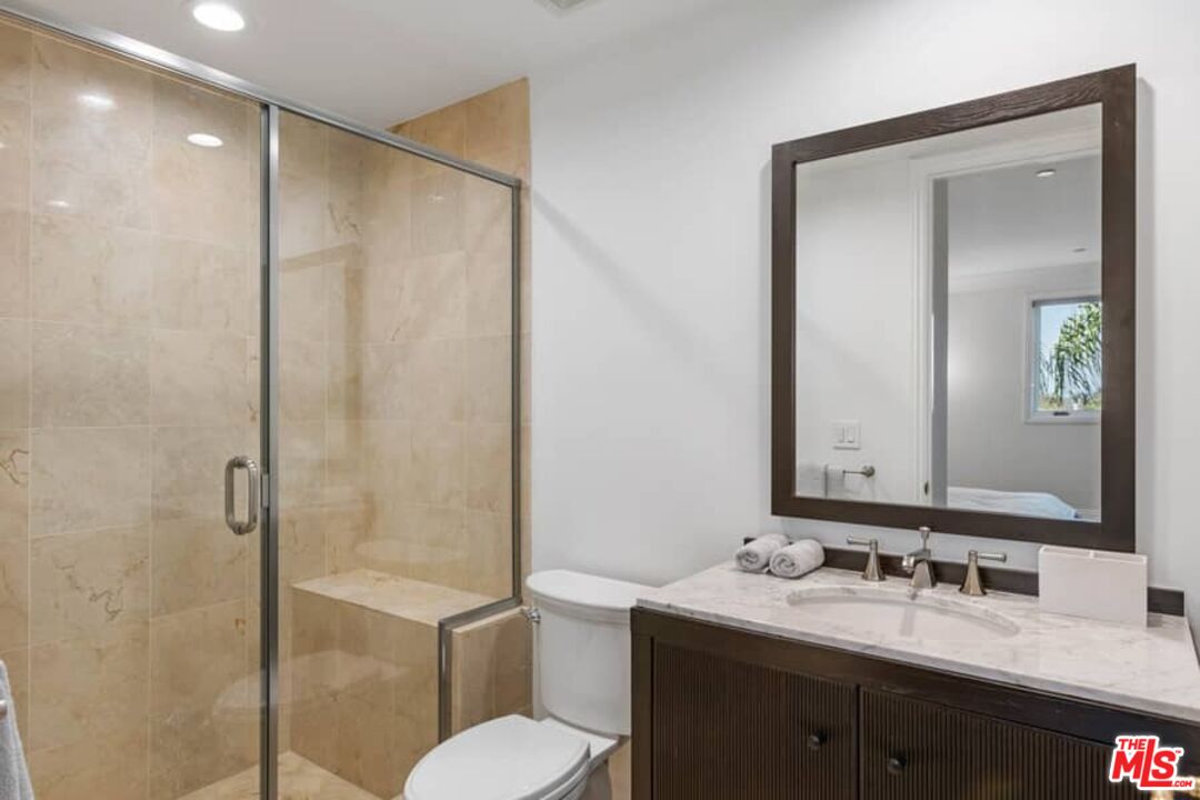 261 South Reeves Drive Beverly Hills, CA 90212 - Photo 29 of 43 a bathroom with a granite countertop sink toilet a mirror and shower