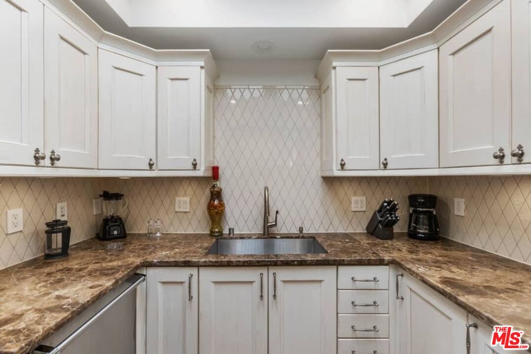 261 South Reeves Drive Beverly Hills, CA 90212 - Photo 10 of 43 a kitchen with granite countertop white cabinets and sink