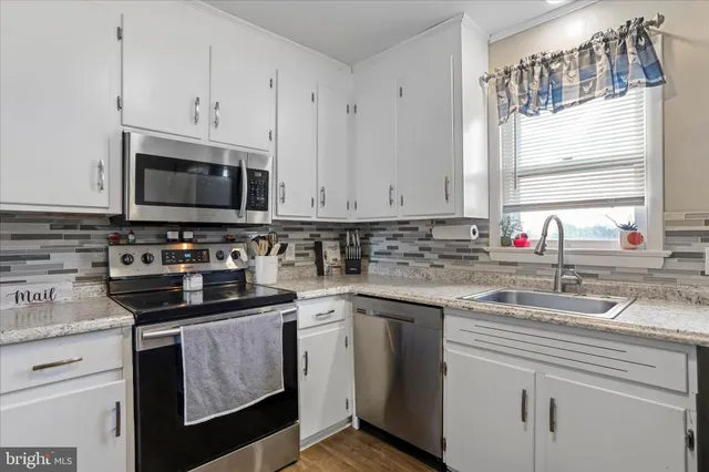 a kitchen with stainless steel appliances granite countertop a sink a stove and a microwave