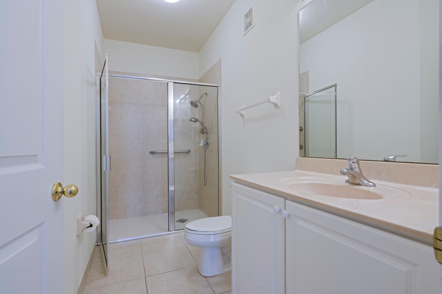 1561 Southeast Hampshire Way, Unit 104 Stuart, FL 34994 - Photo 18 of 23 a bathroom with a sink a toilet and shower