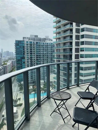a view of a city from a chairs and table in the balcony