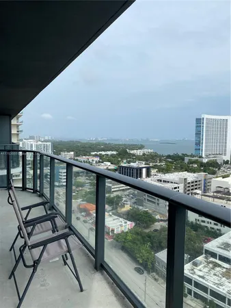 a view of a balcony with wooden chairs and city view