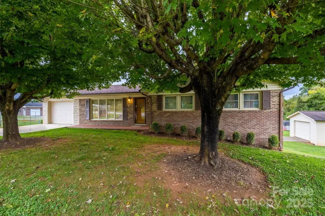 a view of a yard in front of a house with large tree