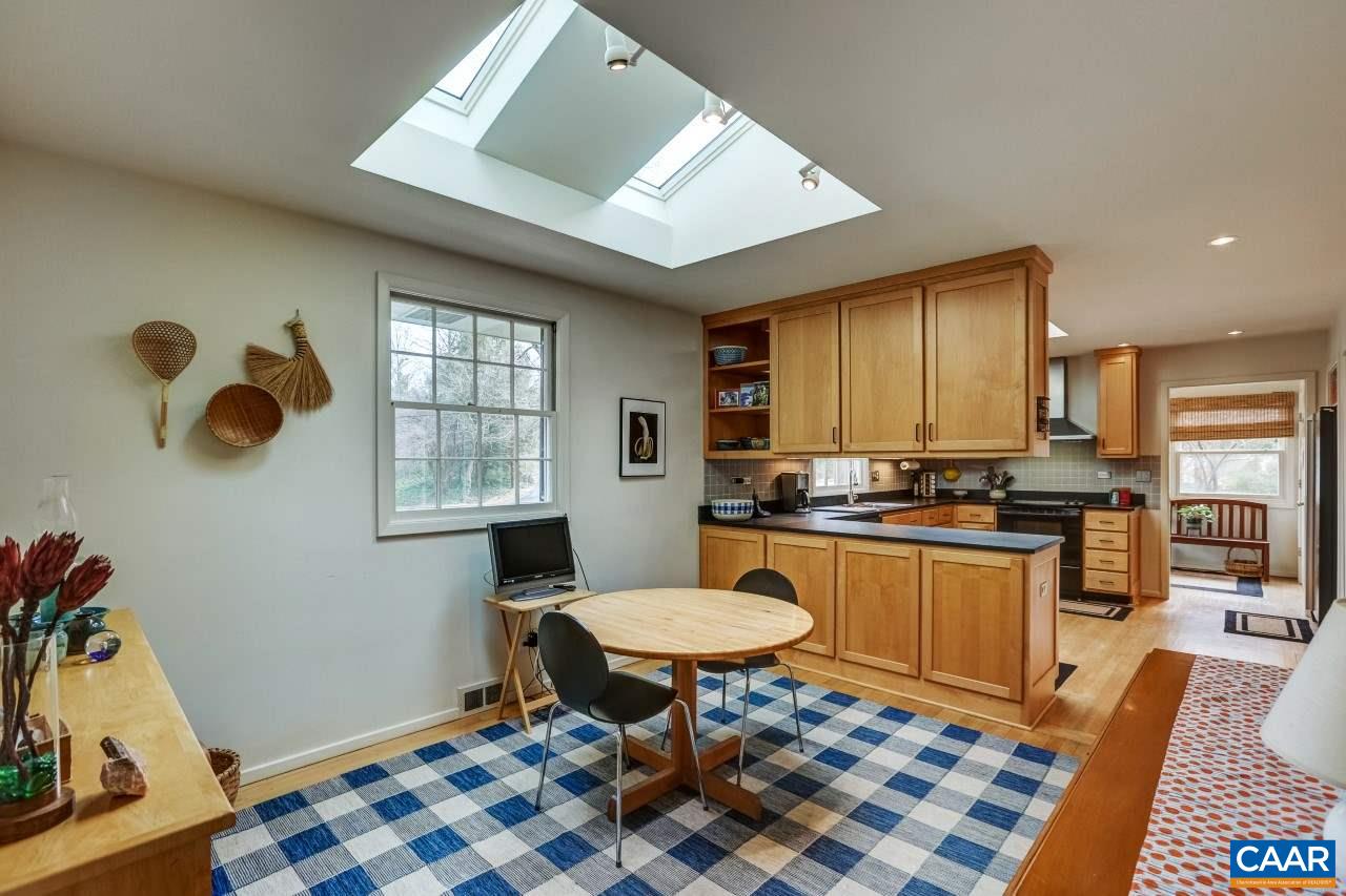 1503 Rugby Road Charlottesville, VA 22903 - Photo 7 of 40 a kitchen with stainless steel appliances kitchen island granite countertop a sink a stove a dining table and chairs with wooden floor