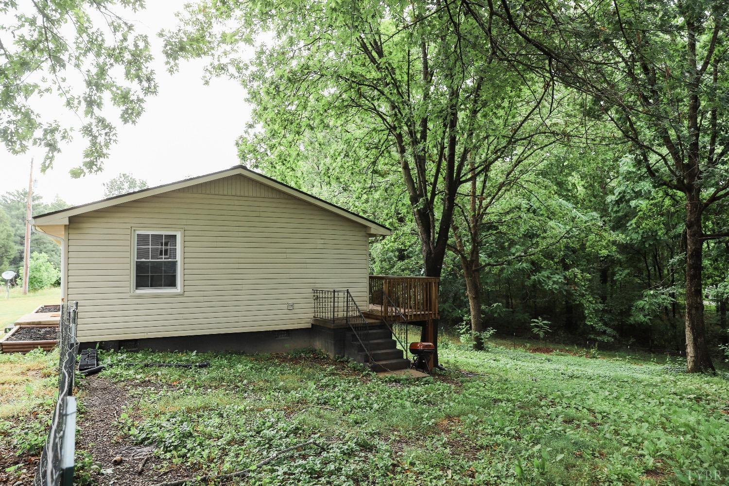 483 Pauls Road Rustburg, VA 24588 - Photo 4 of 21 a backyard of a house with lawn chairs plants and large tree