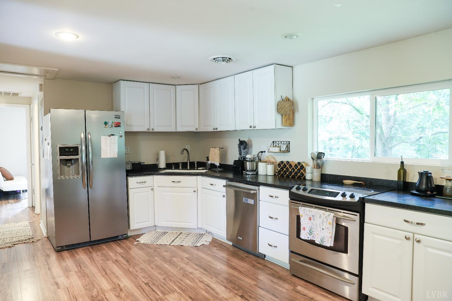 483 Pauls Road Rustburg, VA 24588 - Photo 10 of 21 a kitchen with stainless steel appliances granite countertop a stove a sink dishwasher a refrigerator and white cabinets with wooden floor
