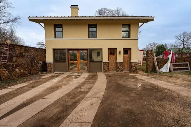 a view of a house with a barbeque and large trees