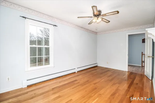 a view of an empty room with wooden floor and a window