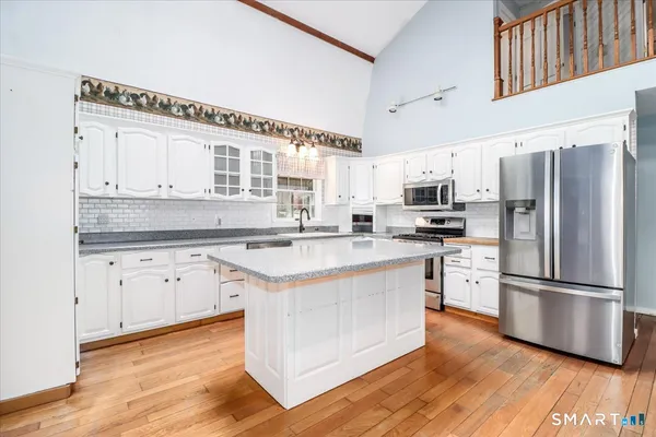 a kitchen with stainless steel appliances granite countertop a refrigerator a stove a sink and white cabinets