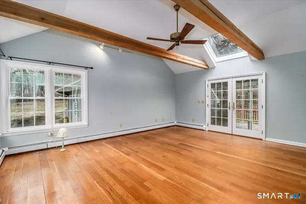 a view of an empty room with a window and wooden floor