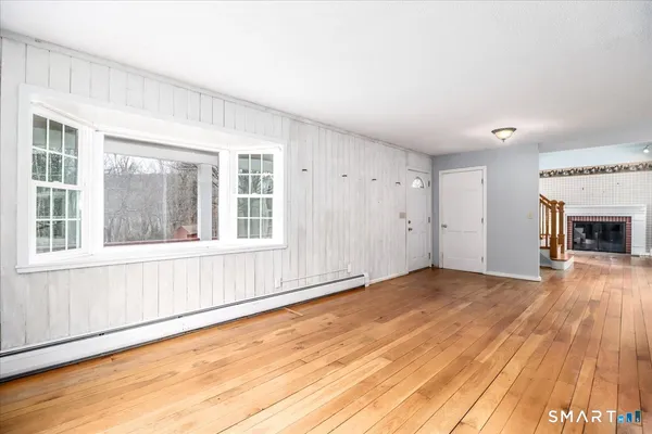 a view of an empty room with wooden floor and a window