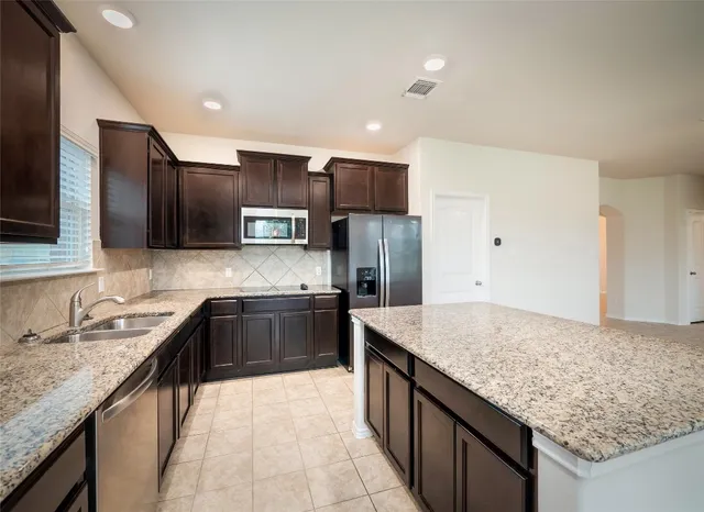a large kitchen with granite countertop stainless steel appliances and a sink