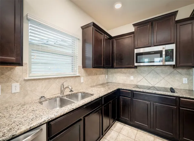 a kitchen with granite countertop stainless steel appliances a sink stove top oven and granite counter space