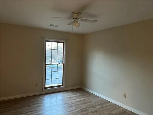 an empty room with wooden floor and windows