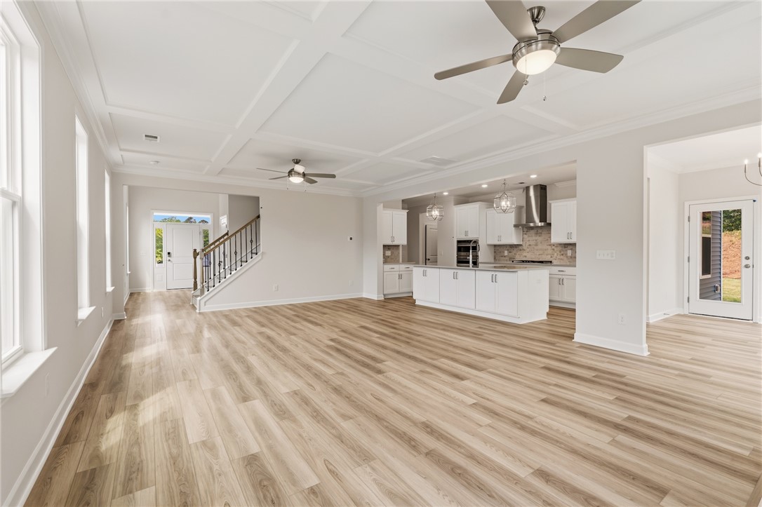 This bright, open-concept interior features wood flooring, a modern kitchen, and an elegant staircase.