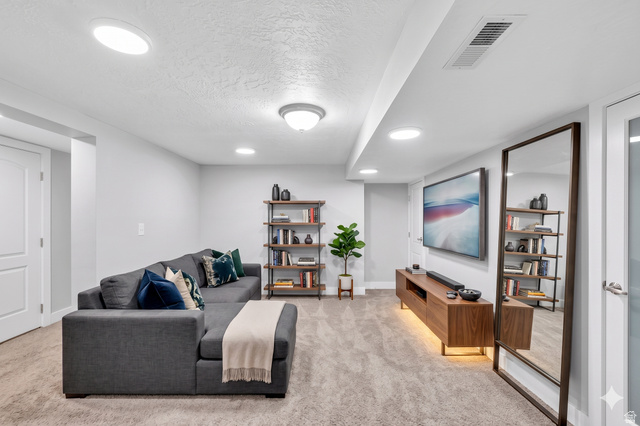 7879 Oak Street Midvale, UT 84047 - Photo 17 of 32 Recessed lighting illuminates this flexible living area with neutral carpeting, white walls, and a modern wood media console featuring integrated lighting