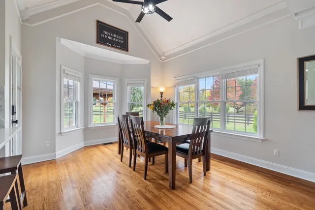 a large kitchen with granite countertop a stove a sink dishwasher a dining table and chairs with wooden floor