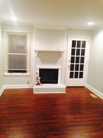 an empty room with wooden floor and fireplace