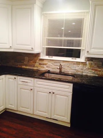 a kitchen with granite countertop white cabinets and sink