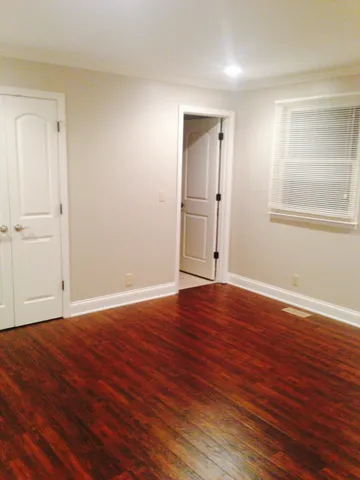 a view of empty room with wooden floor and window