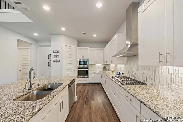 a large kitchen with stainless steel appliances granite countertop a lot of counter space and wooden floors