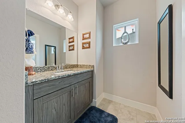 a bathroom with a granite countertop sink and a mirror