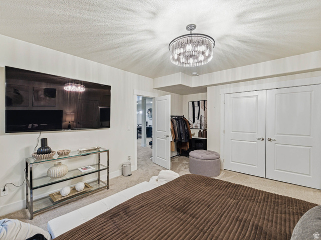 1154 Sunset Dunes Way Draper, UT 84020 - Photo 46 of 50 Bedroom with carpet floors, a textured ceiling, hanging lights, and a closet