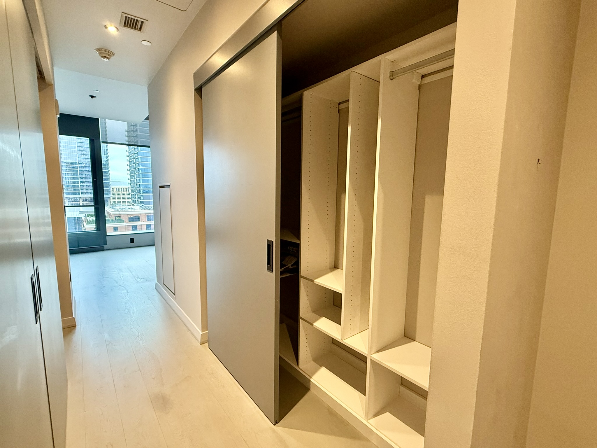 210 Lavaca Street, Unit 2809 Austin, TX 78701 - Photo 14 of 17 An organized closet offers ample storage space, complementing the clean lines of the hallway and natural light from large windows.